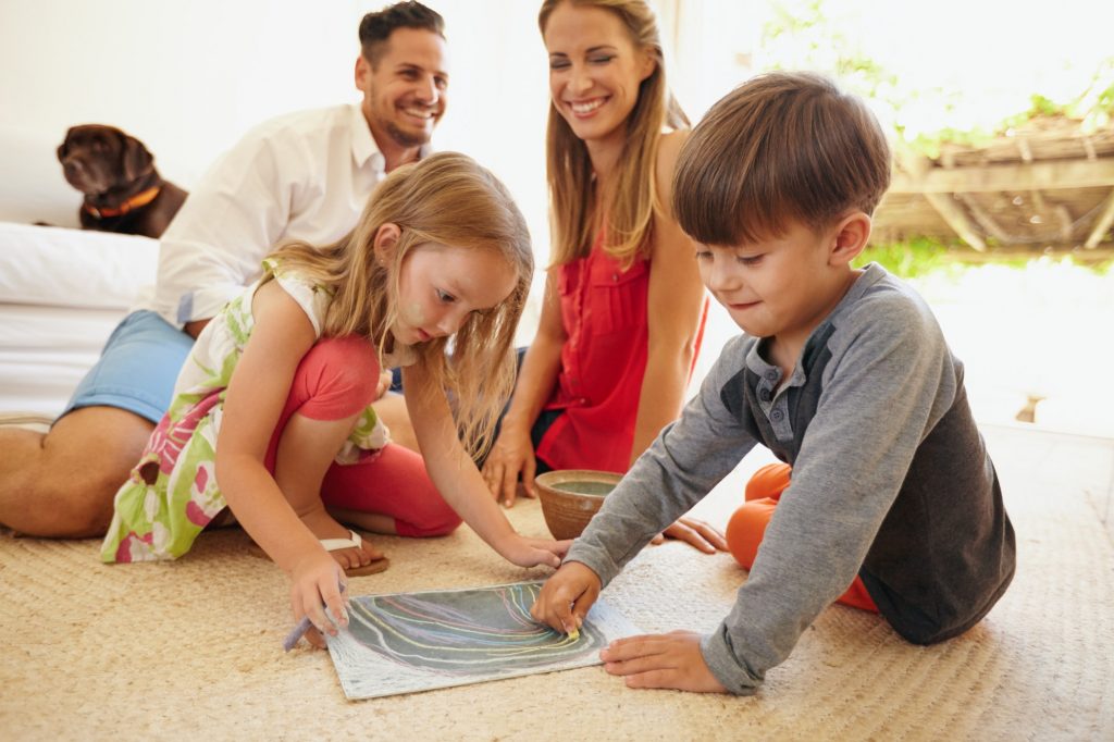 Children drawing with their parents in living room